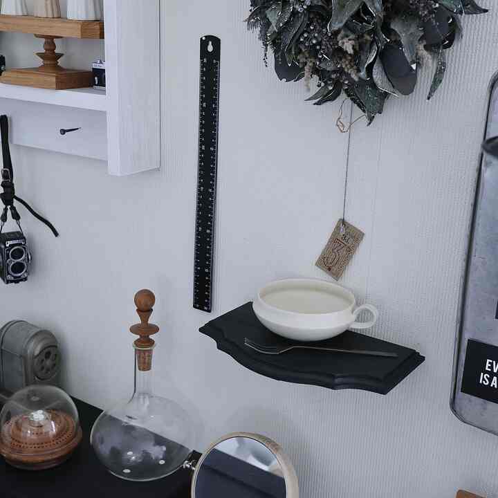 白い壁と黒のブラケットライトが配置されたシンプルなキッチンの壁、トレイの上に皿などの小物が置かれた雰囲気のあるインテリア