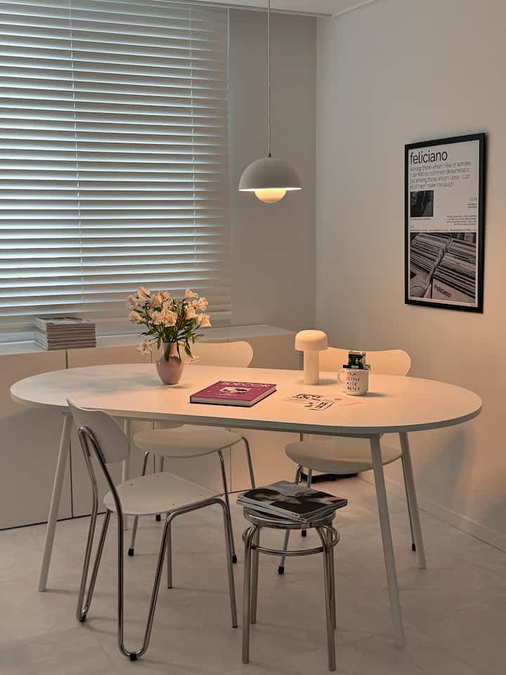 白を基調としたダイニングルーム、中央に食卓と椅子を配置し、ペンダントライトとテーブルランプが雰囲気あるインテリア