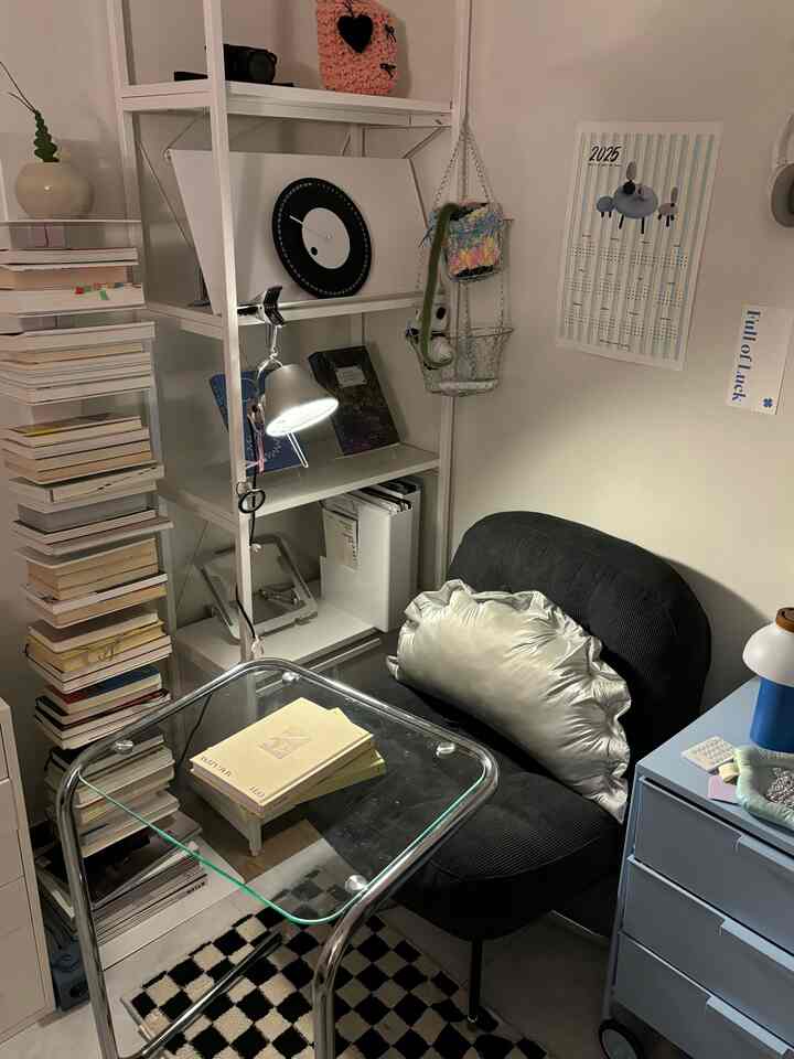 白と黒のトーンでまとめられたコンパクトな書斎空間、ミニマルなブラックのアームチェアと本棚が配された落ち着いた読書スペース