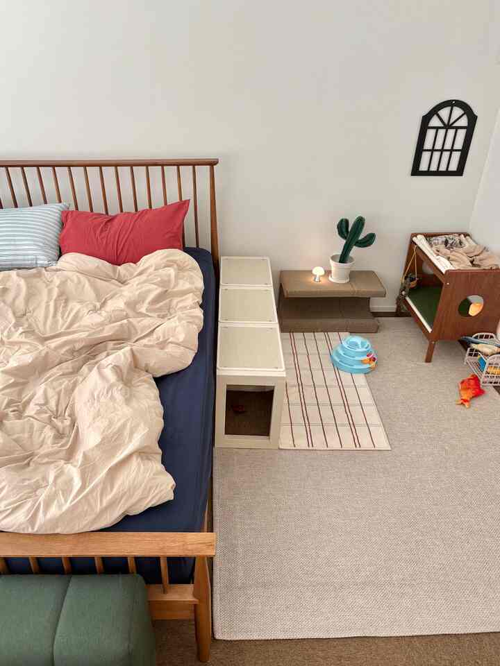 ナチュラルトーンと木目調が調和した寝室、ベッドと猫用ペット家具が配置された居心地の良い整った空間