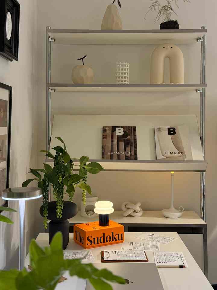 白を基調としたミッドセンチュリーモダンスタイルのホームオフィス、金属製の棚とデスクが配置された空間