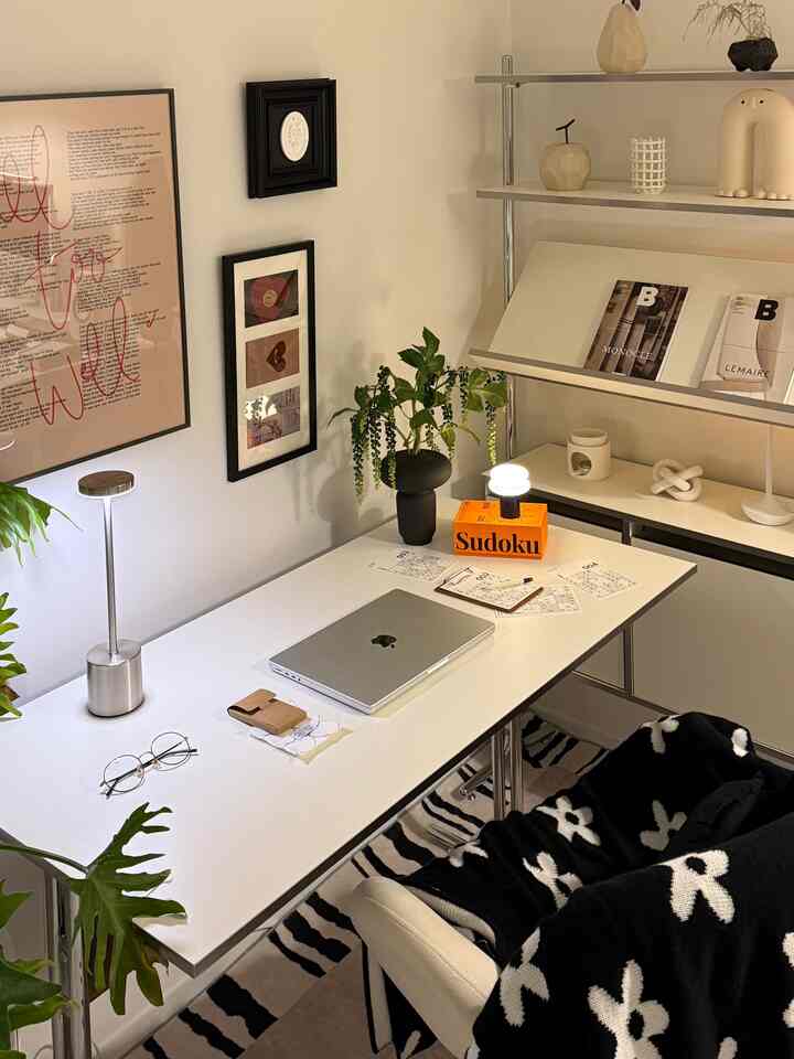 白と黒のトーンが特徴のホームオフィス、広いデスクとオフィスチェア、収納棚と植物が配置された雰囲気のある空間