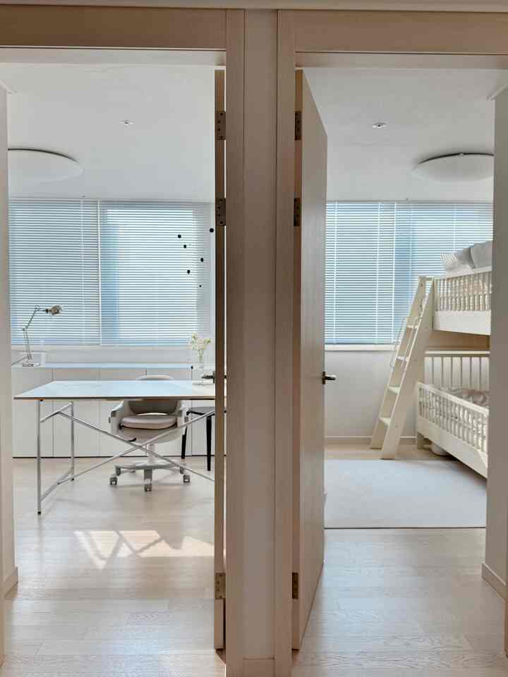明るく清潔感のあるホワイトとナチュラルカラーの子供部屋と書斎、二段ベッドと勉強机が配置されたミニマルなインテリア空間