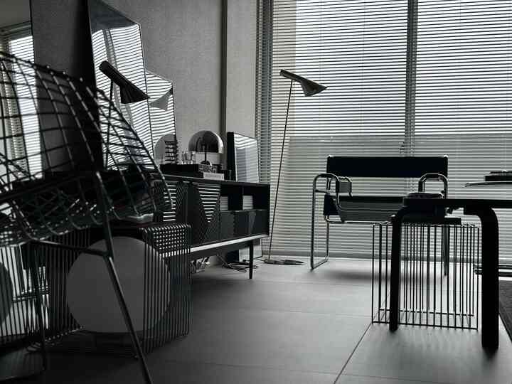 Modern black-toned home office featuring office chair, desk, and blinds in a clean minimalist interior