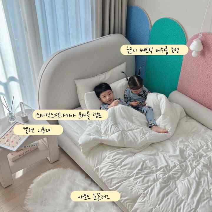 柔らかいアイボリーの寝室、中央にベージュのベッドと白い掛け布団があり、二人の子供が横たわる雰囲気のある空間