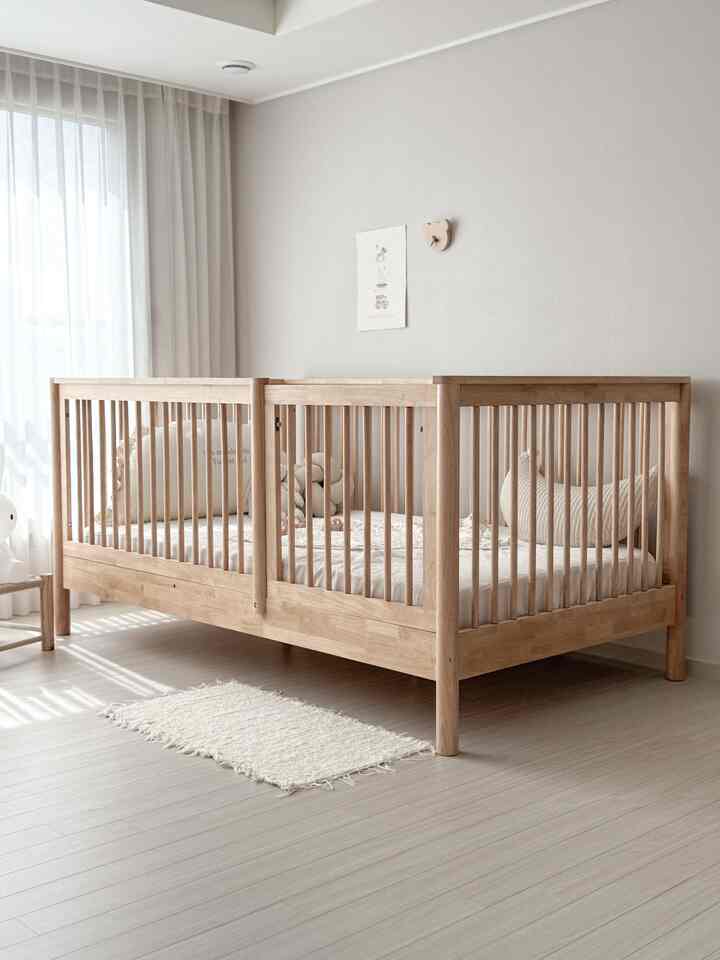 ナチュラルなベージュ色調の子供部屋に木製のベビーベッドが配置された温かみのある空間