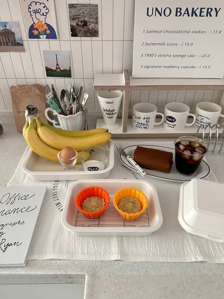 白とベージュのトーンのキッチン、さまざまなマグカップとカトラリーが配置され、赤ちゃんのおやつが準備された雰囲気のある空間