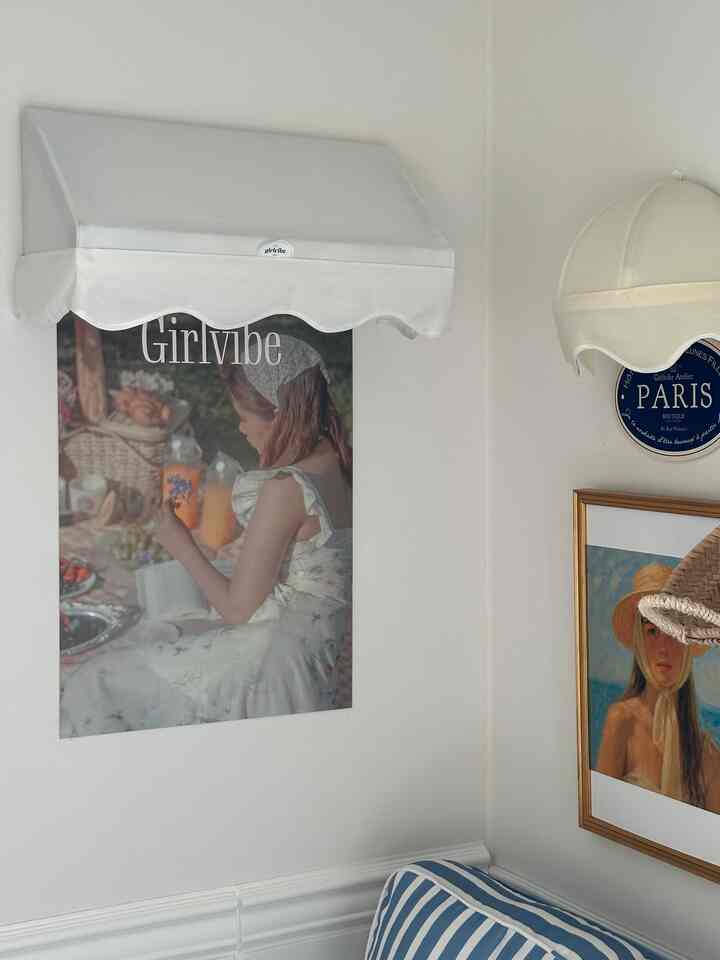 白い壁とパステル調の装飾が調和するコーナースペース。フレンチカントリースタイルの額縁と壁デコが配置された雰囲気のあるインテリア