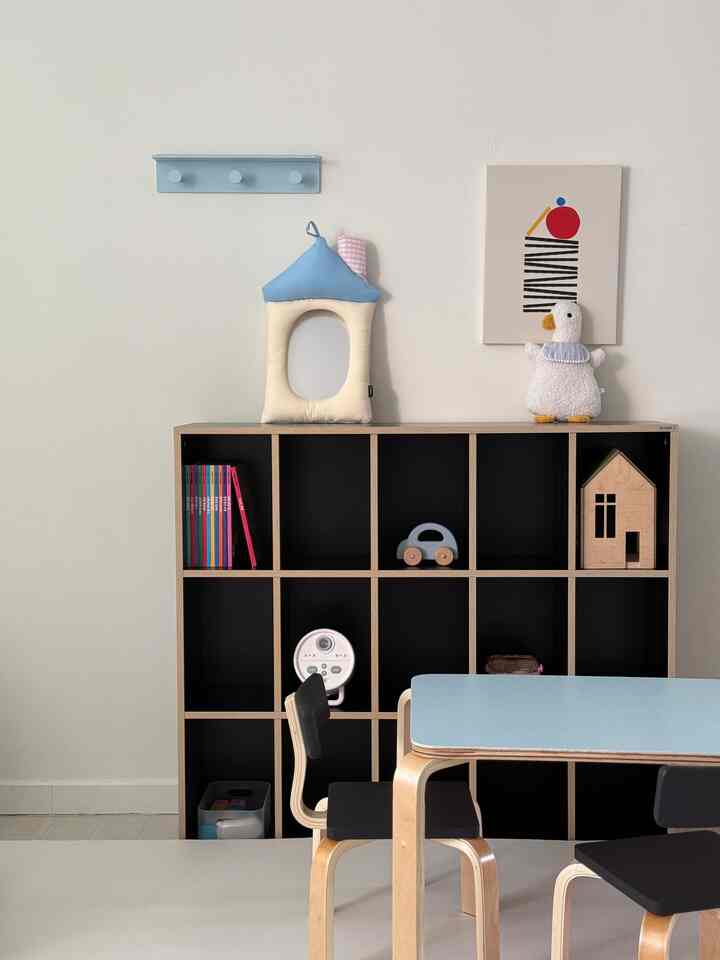 明るい木材と黒の本棚が配置された子供部屋、青い子供用机と椅子が置かれた清潔感のあるインテリア
