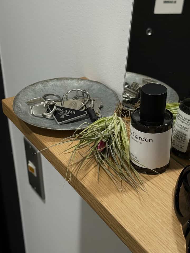 Natural wood tone wall-mounted shelf with perfume and mirror, simple entrance accessory space