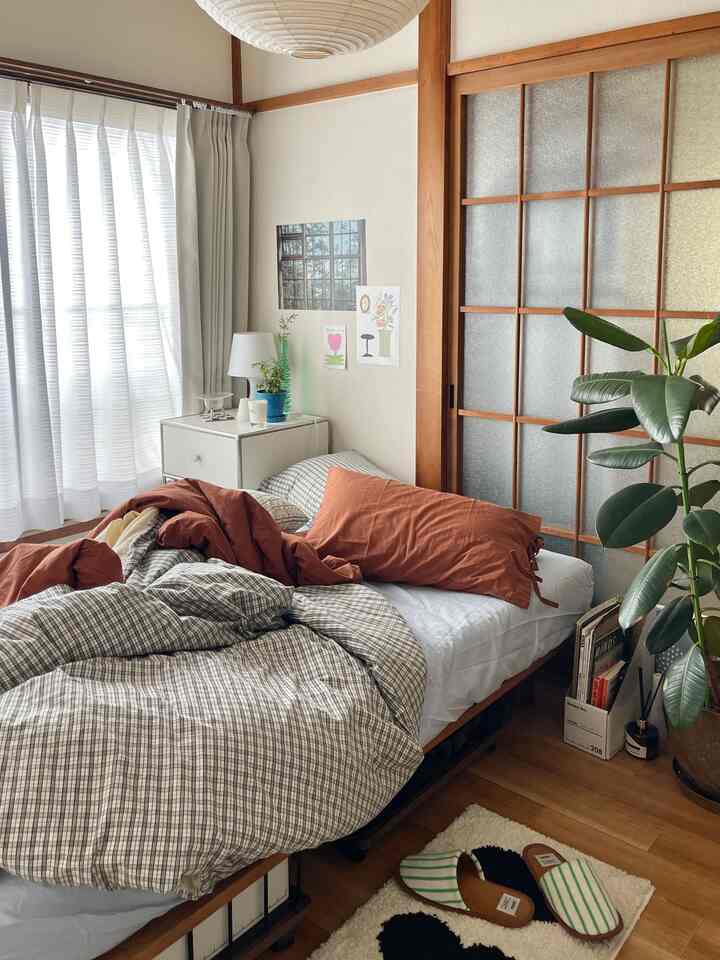 Beige and brown toned 1DK Japanese-style bedroom featuring a MUJI bed, side table, and plants, creating a cozy atmosphere