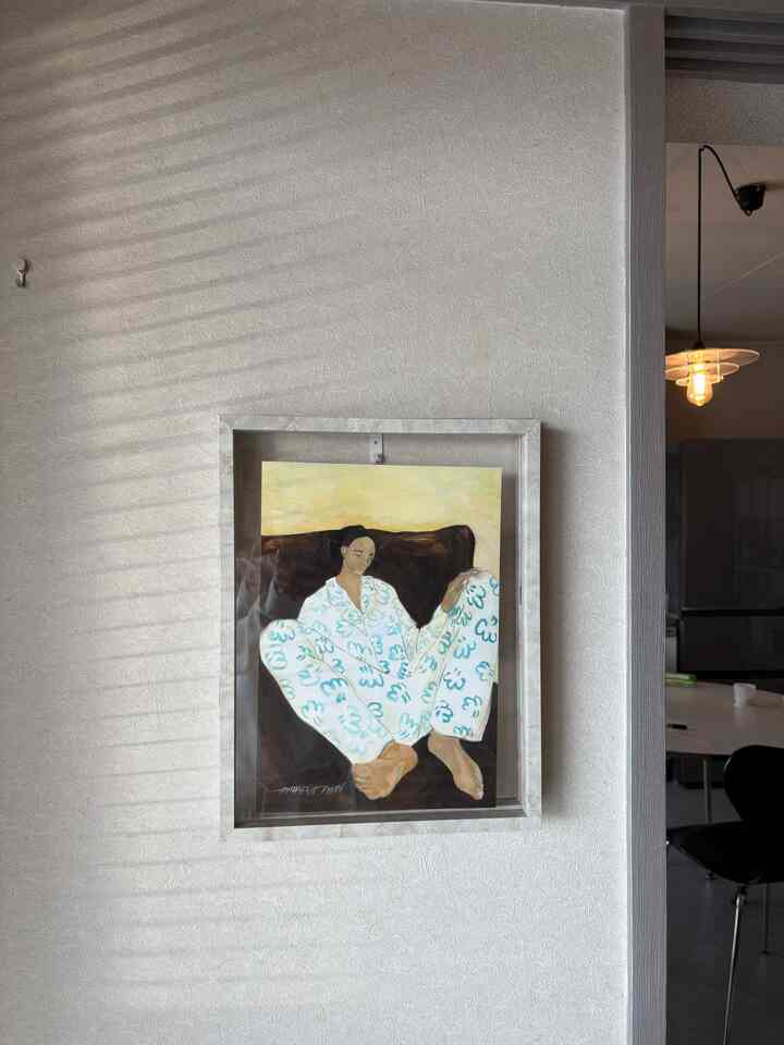 ベージュの壁にポスターが掛けられた、自然光が柔らかく差し込むシンプルなインテリア