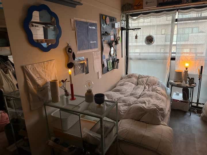 ナチュラルカラーのワンルーム寝室、イケアの棚とナイトテーブルが配置された雰囲気のあるインテリア