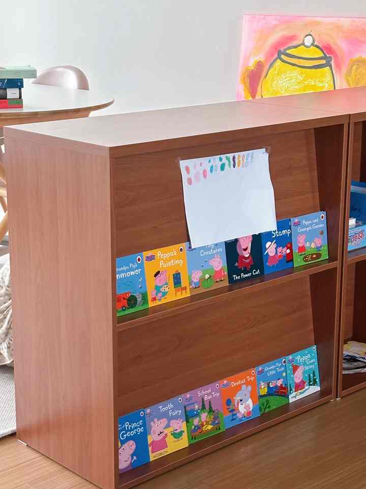 ブラウン調の子供部屋、中心に子供用本棚が配置され、一部ダイニングスペースが見える温かみのある空間