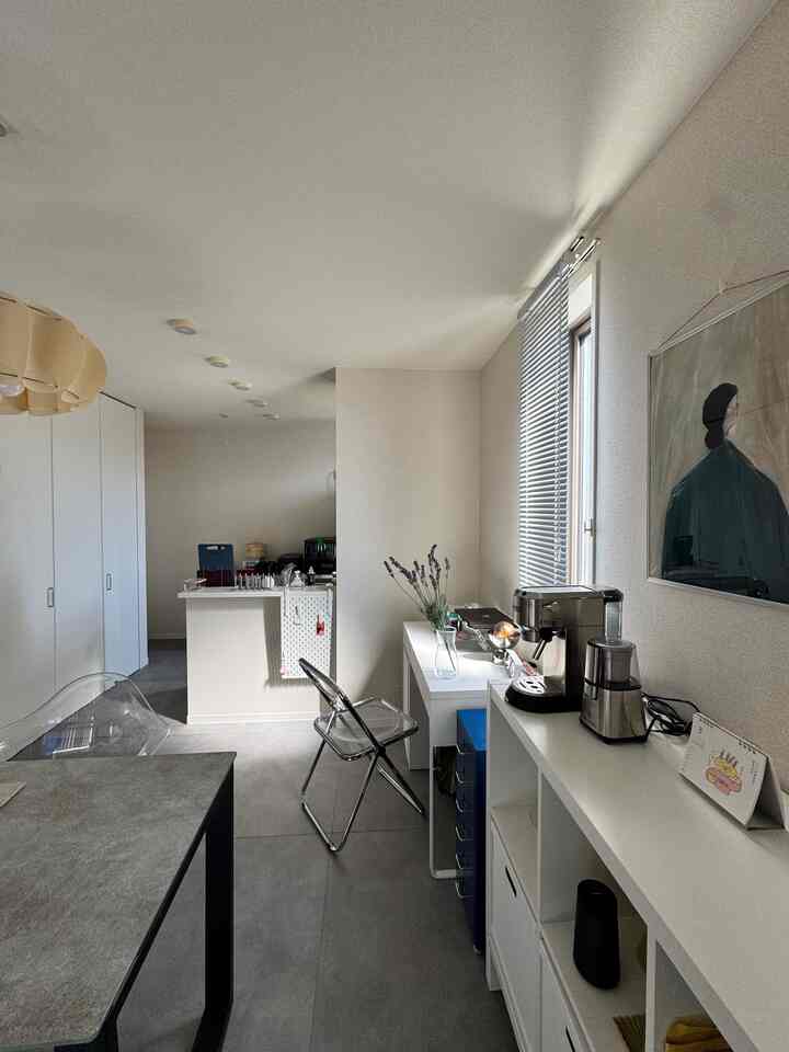 Modern interior with gray and white tones showcasing kitchen and living room, featuring dining table and desk in a cozy atmosphere