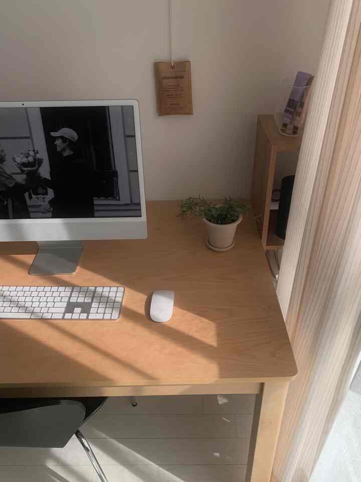 温かみのあるベージュトーンの木製デスクとiMac、シフォンカーテンが配置されたコンパクトなホームオフィスのインテリア