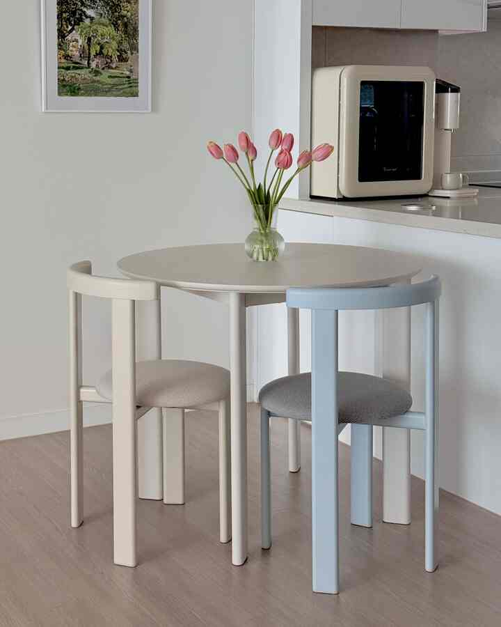 白を基調としたキッチン、丸いダイニングテーブルとベージュとライトブルーの椅子が配置された落ち着いた雰囲気のインテリア