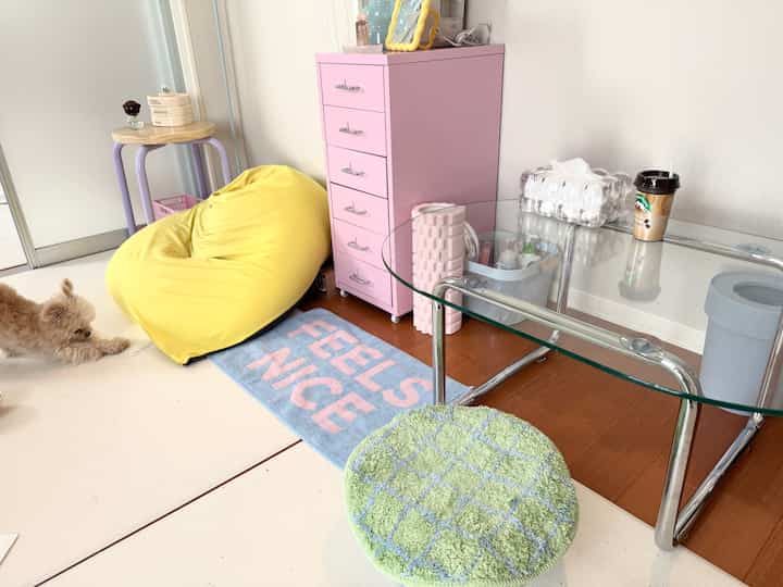 黄色のビーンバッグとピンクの引き出しが置かれた狭くて居心地の良いリビング、床でストレッチする犬