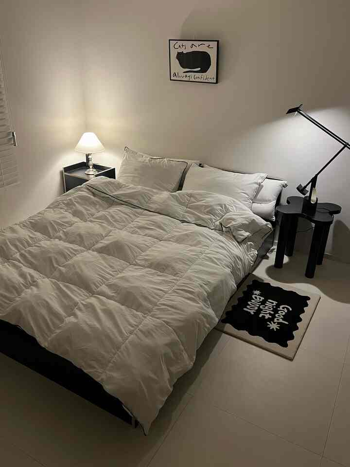 白と黒のトーンの寝室、猫のポスターと二つのテーブルランプが配置されたホテルライクな雰囲気のインテリア