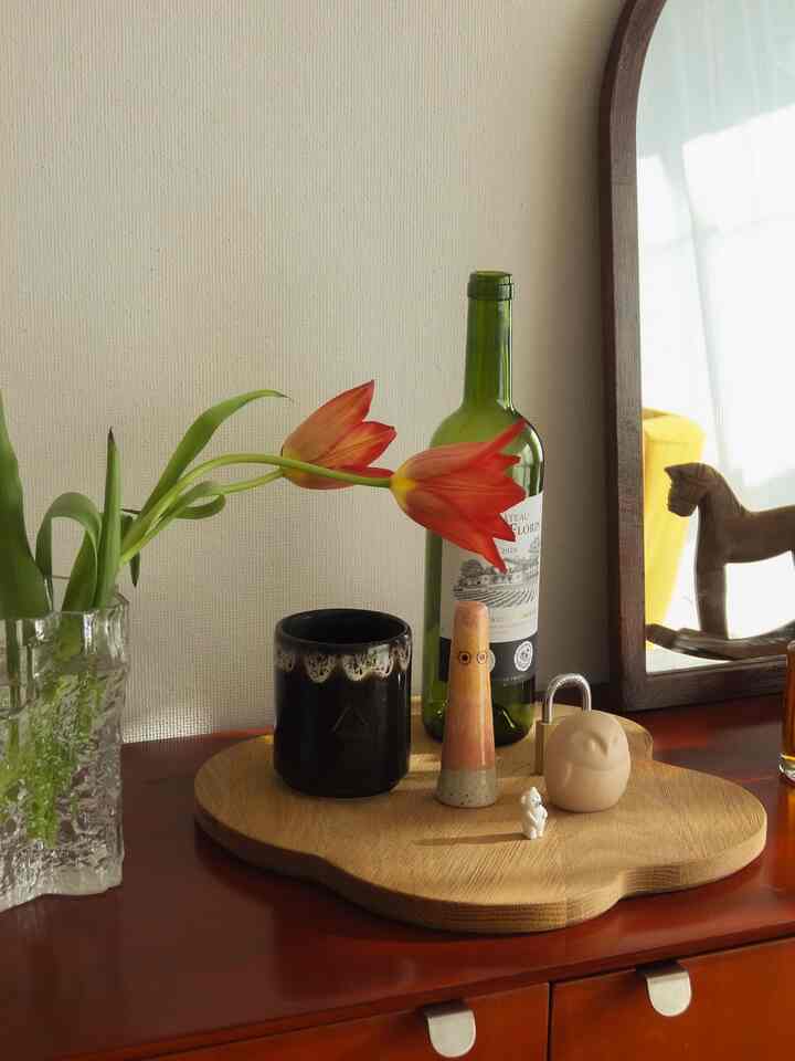 ブラウン系の木目調のディスプレイスペース、花瓶とワインボトル、小さなオブジェが配置された雰囲気のあるインテリア