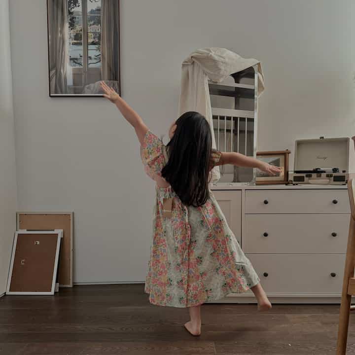 White-walled bedroom with brown wooden floor featuring wardrobe and child in center with warm atmosphere