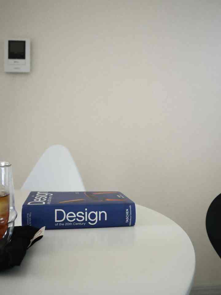 Beige and white toned dining room featuring a book and a glass of tea on a minimalistic table with a clean atmosphere