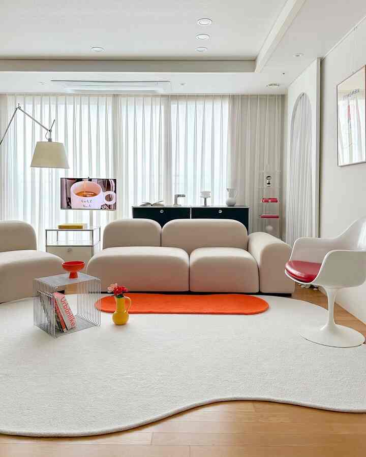 White and beige toned living room featuring curved pebble sofa and heybay rug in a modern interior