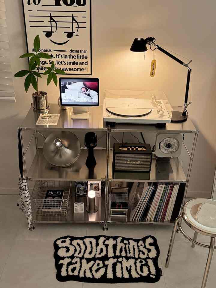 ブラックとシルバーのトーンが調和したホームオフィス、レトロなオーディオとステンレス棚、丸いスツールが配置された雰囲気のあるインテリア