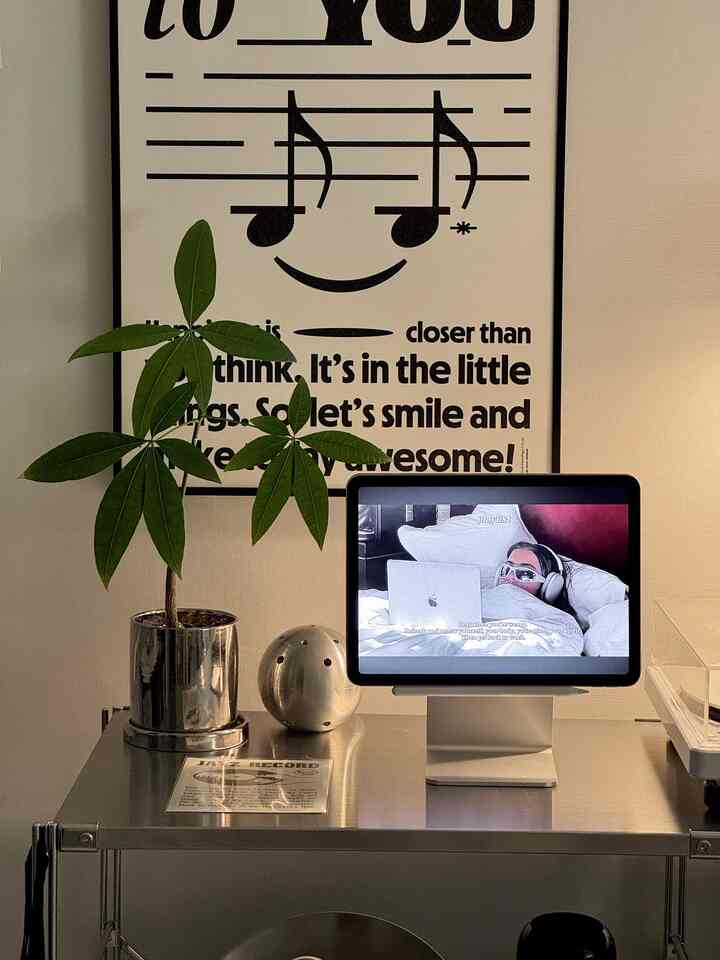 シルバーのスチール棚に植物とタブレット、音楽のモチーフポスターが配置されたミニマルかつモダンなホームオフィス空間