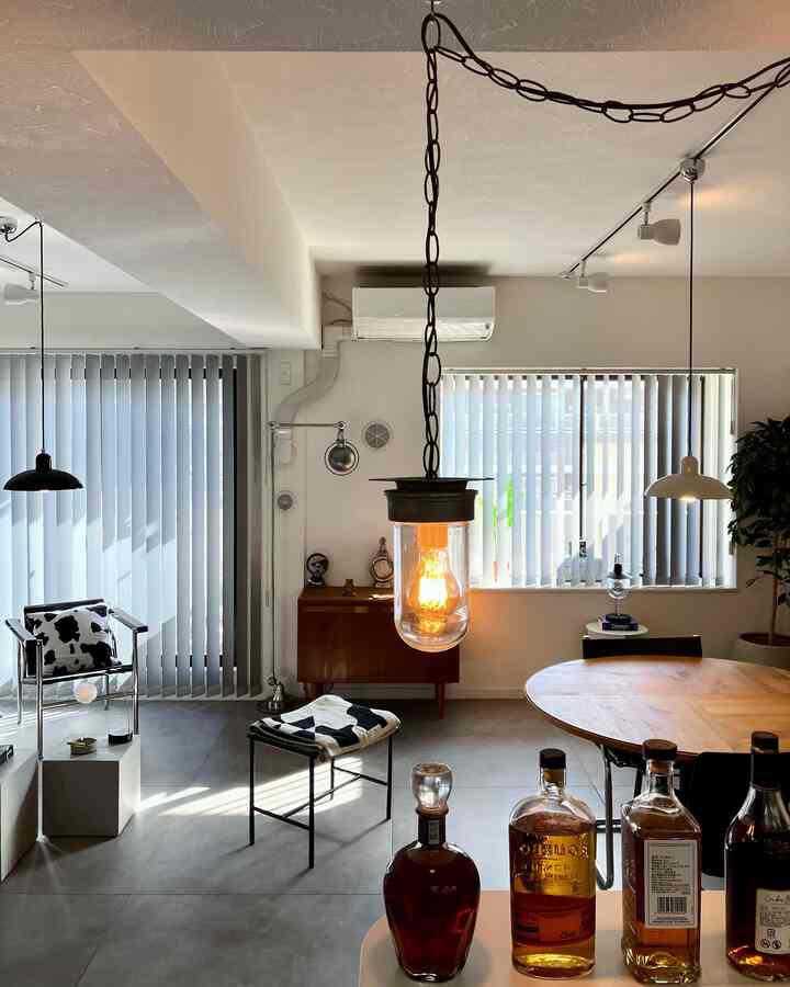 Bright white walls and wood-tone round dining table with industrial pendant lights in a vintage-style dining room