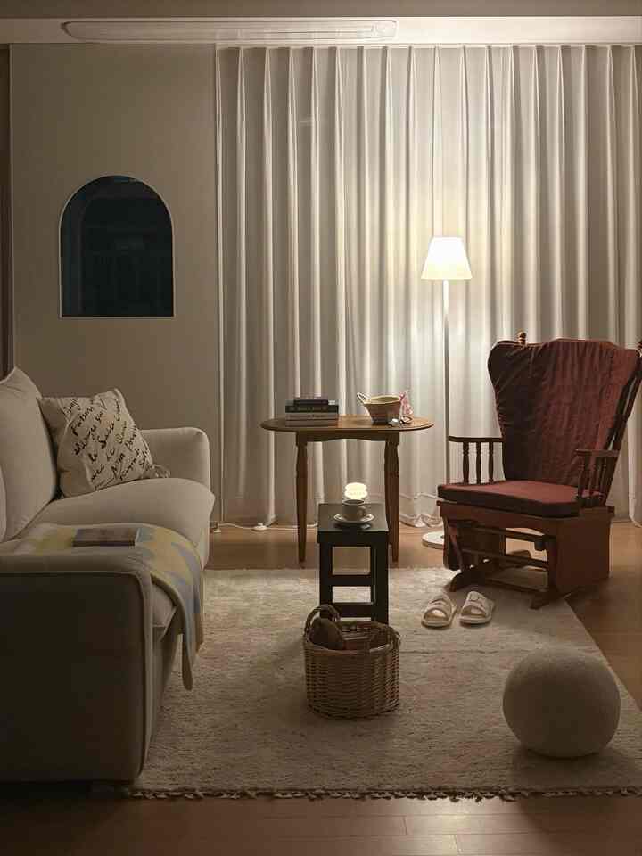 暖かいベージュと木目調のリビング、ソファと木製テーブル、アームチェアが配置された落ち着いた雰囲気の空間