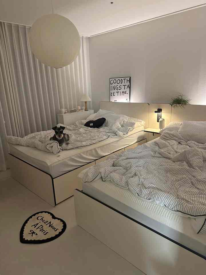 白と黒のトーンでホテルライクな2人用寝室、2つのベッドと小さな犬が置かれた清潔でミニマルな空間