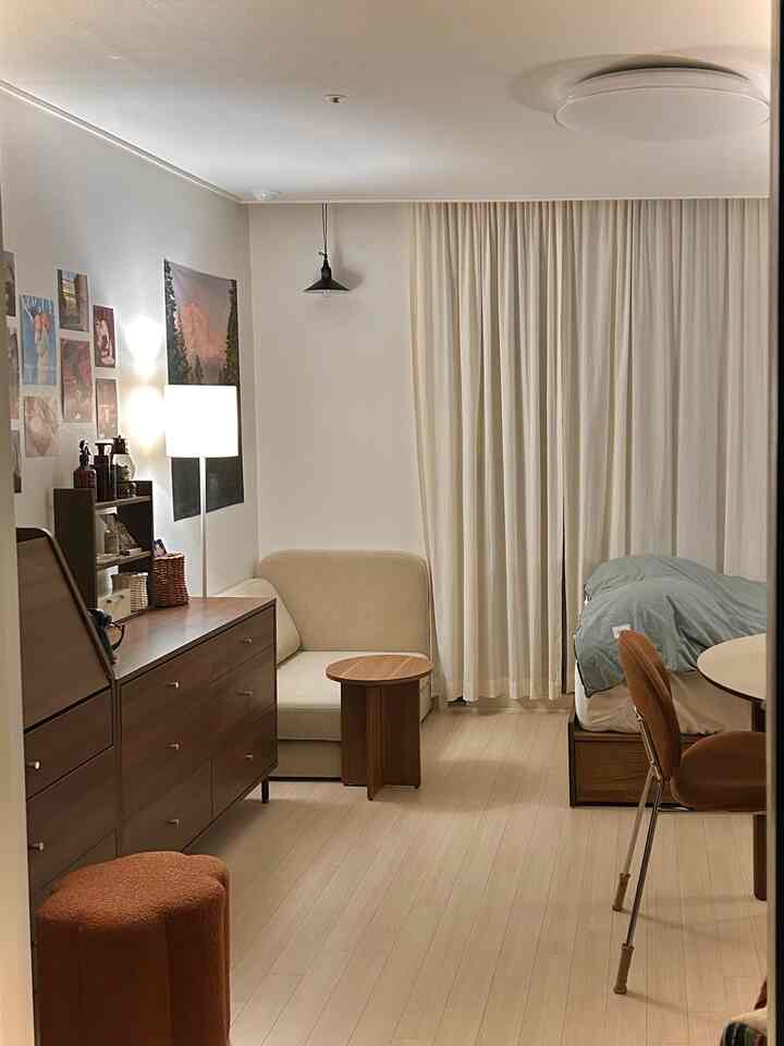 ナチュラルなブラウンとホワイトのワンルーム、ベージュのソファと木製家具が配置された落ち着いた雰囲気のインテリア