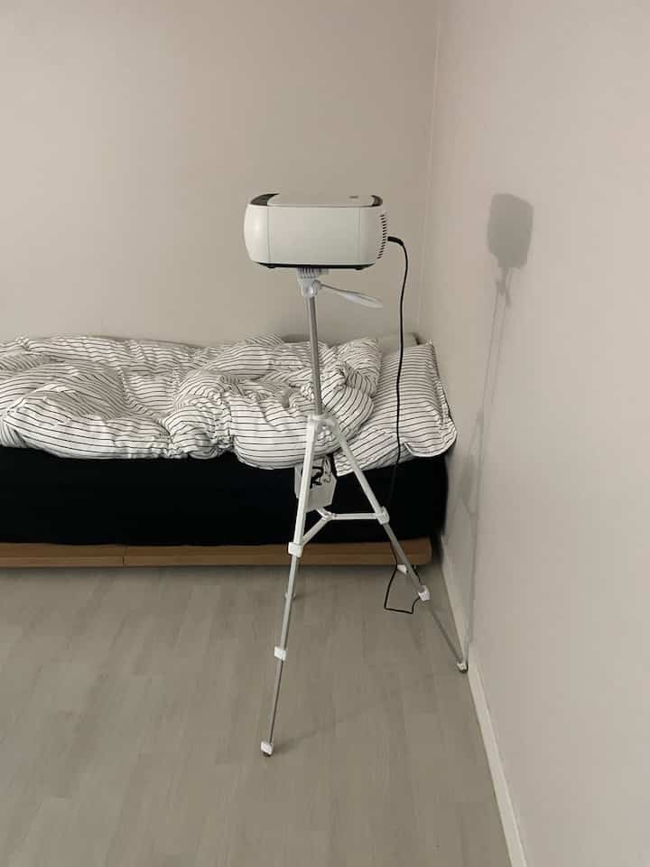 Minimal bedroom in white and black tones featuring a bed and projector setup