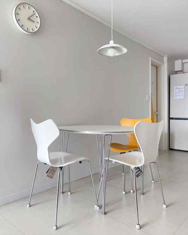 白とシルバーのトーンの円形空間、フリッツ・ハンセンのスーパーエリプティカテーブルとセブンチェア、グランプリチェアが配されたミニマルで北欧風のダイニングインテリア