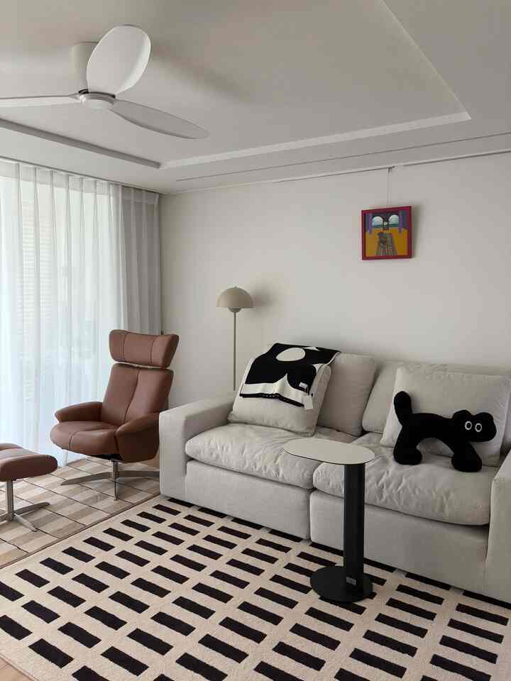 White and beige toned living room featuring modern recliner sofa and geometric pattern rug with a clean atmosphere