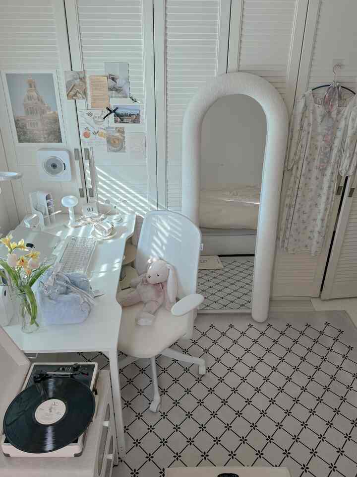 白とベージュのトーンのワンルーム、広いデスクとオフィスチェア、アーチ型のフロアミラーが配置されたシンプルな北欧風インテリア