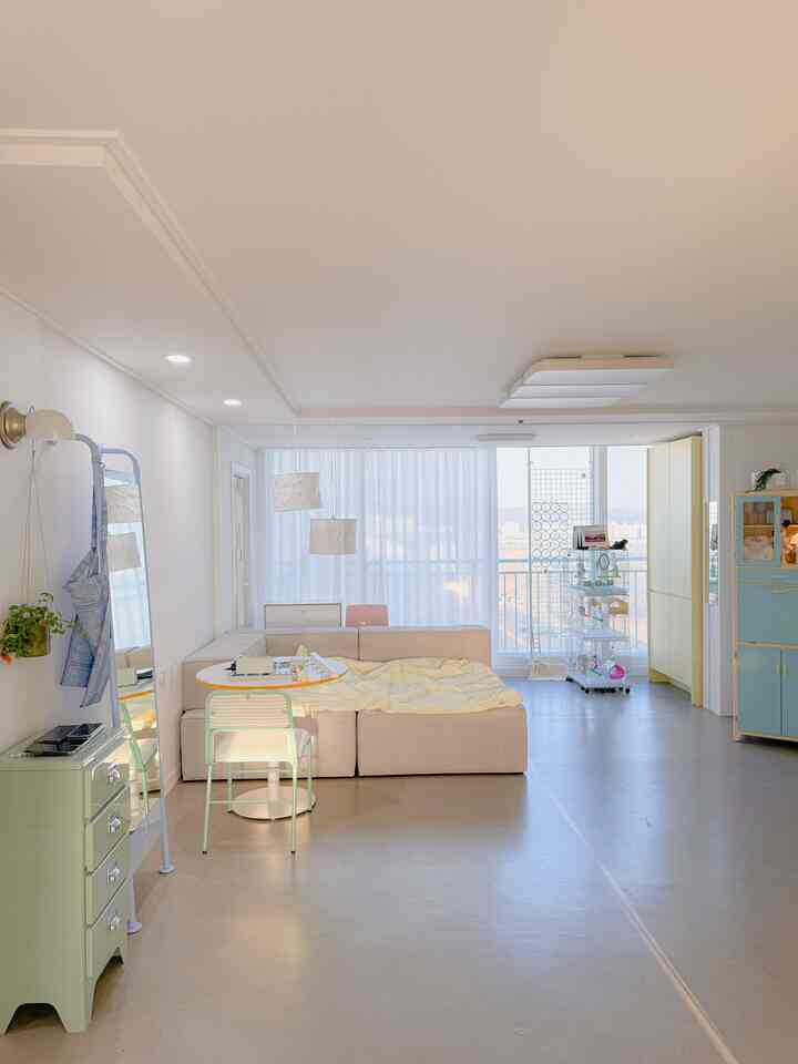 ナチュラルトーンのリビングルーム、ベージュのソファとバルコニーが見える明るくコンパクトな雰囲気のあるインテリア