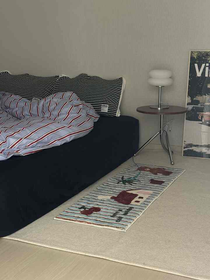 A bedroom in white and navy tones featuring a black bed and striped pillows, creating a modern atmosphere