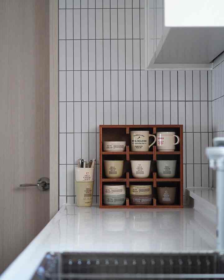白とベージュの色調のキッチン、カップと器の収納棚が整然と配置された雰囲気のあるインテリア