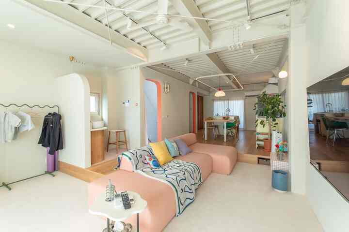 White walls and ceiling with a pink modular sofa and wooden floor in a simple modern living room for a 4-person household