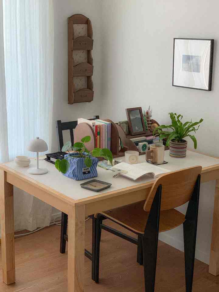 アイボリーとベージュのトーンの小さなホームオフィス、ナチュラルモダンなインテリアで植物と本が配置されたデスク