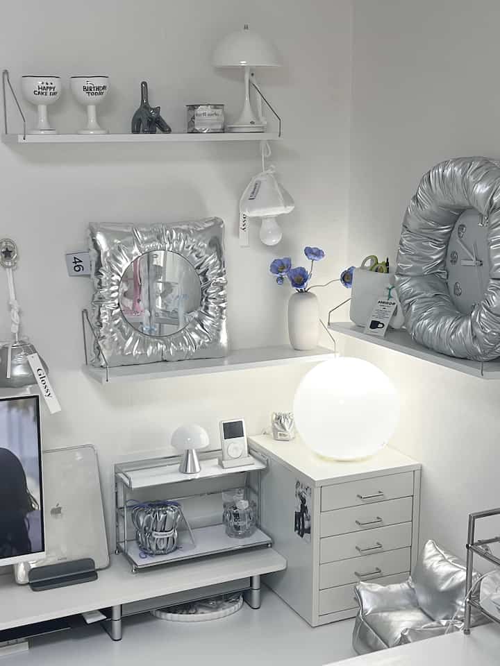 A white and silver toned studio apartment living room featuring minimal furniture and cat-themed decor in a modern space