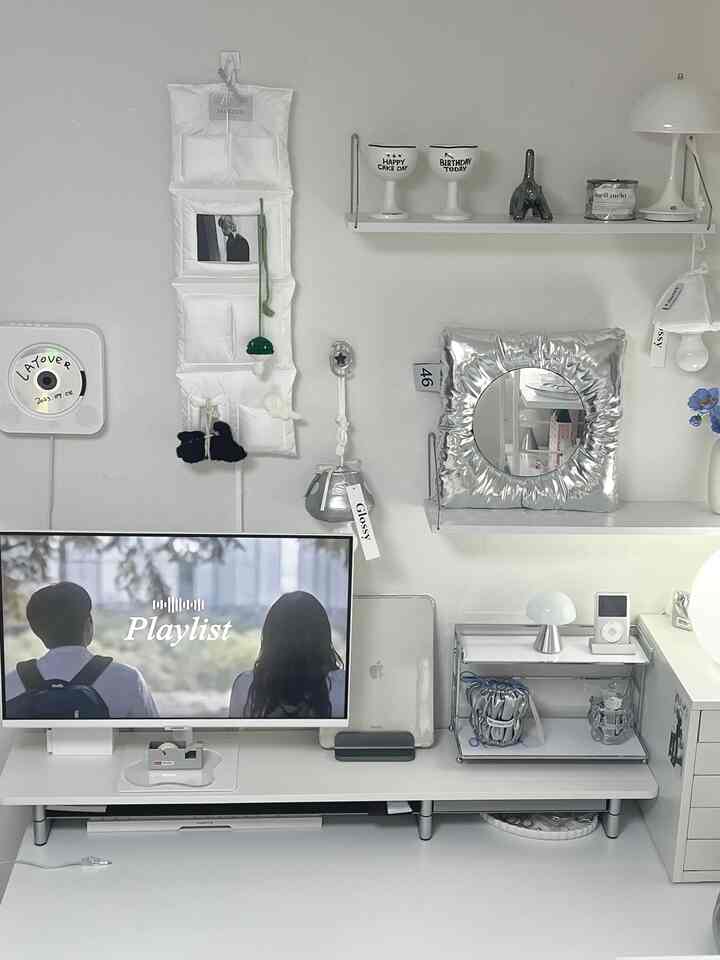 Modern home office space in white and silver tones featuring wall storage and mirror objet in a clean single household interior
