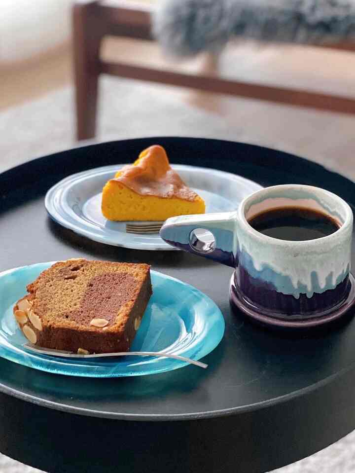 黒いテーブルに青い皿とマグカップが置かれた、おうちカフェ風のリビング空間