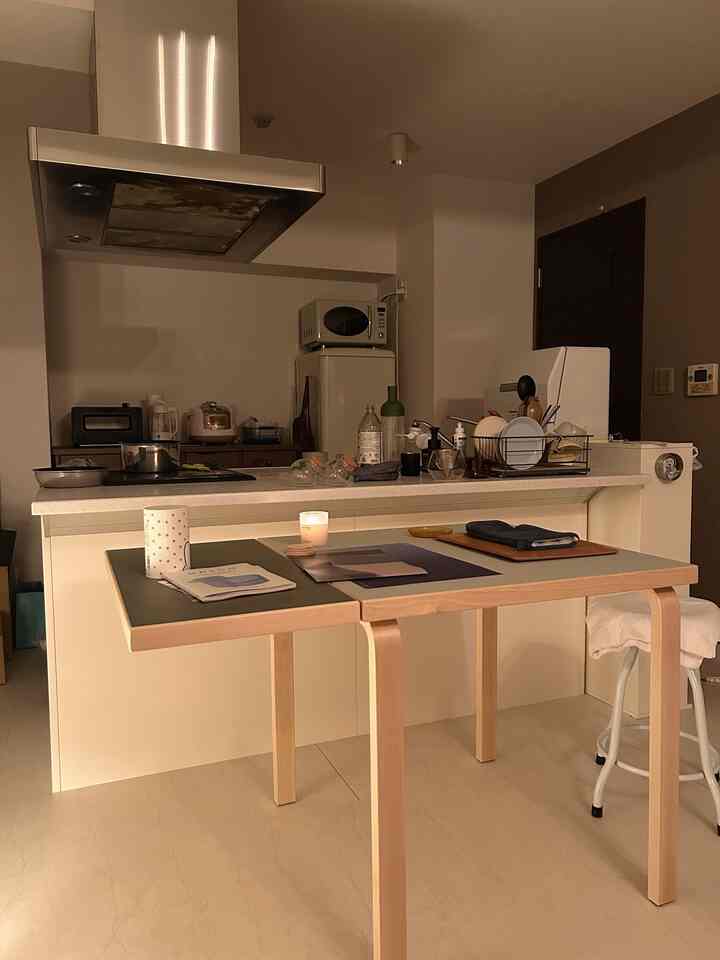 白い壁と木目調のダイニングテーブルが配置された、一人暮らし向けのシンプルな1LDKキッチンとダイニング空間