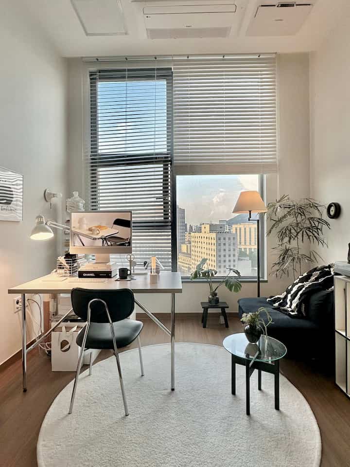 白と木目調が調和したホームオフィス空間、コンピュータデスクとソファが配置された居心地の良い小さな部屋