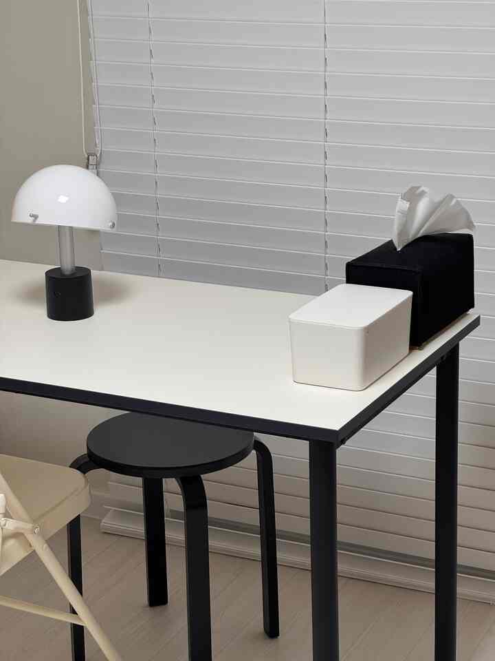 Modern single household dining table and stool with white top and black frame in a clean small room