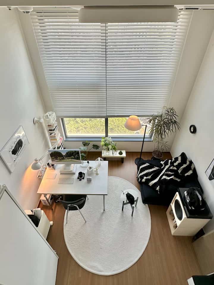 白と茶色のトーンのホームオフィス、シンプルなデスクとソファ、植物が配置された雰囲気のあるインテリア