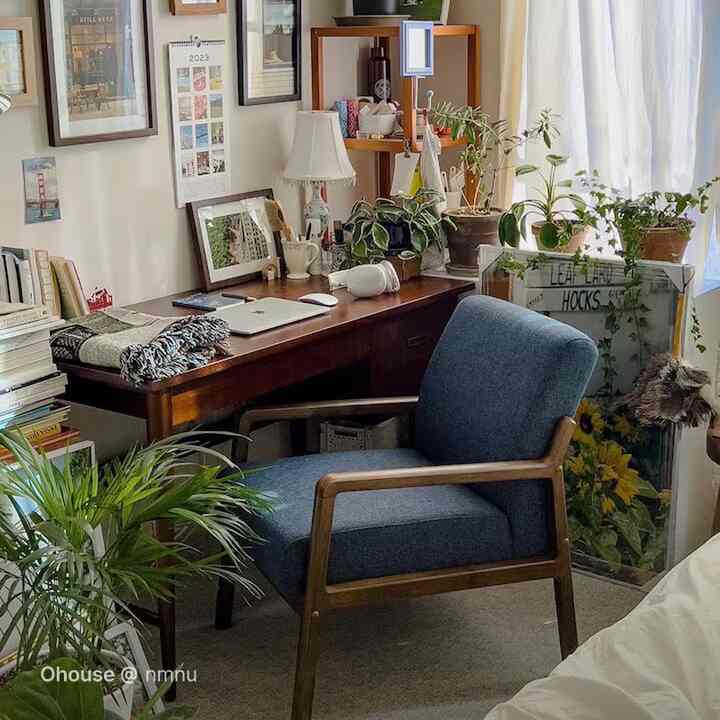 ナチュラルな色調の小さなホームオフィス、木製デスクと青いアームチェア、植物が調和する雰囲気のあるインテリア